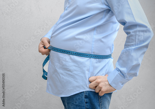 A big belly with a slim figure, a man measures the circumference of his belly