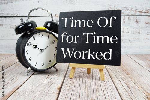 Time Off for Time Worked text with easel and alarm clock on wooden background photo