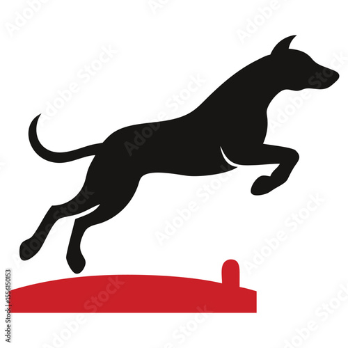 Silhouette of a black dog joyfully leaping over a red obstacle in vibrant action