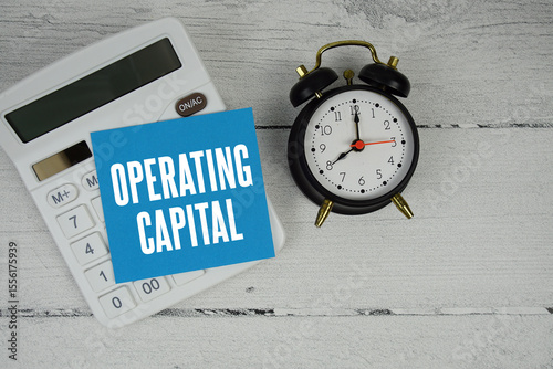 Operating Capital text with calculator and alarm clock  on wooden background
