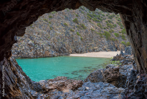 I walk through a cave to reach a small beach with turquoise waters on the island of Sardinia.