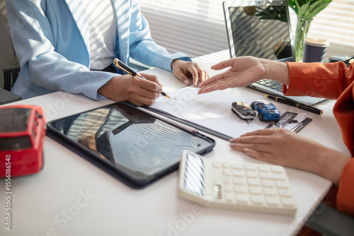 car dealer handing over keys female customer after successfully signing car sales contract. Concept of signing car sales contract and handing over keys so that customer can take car back immediately.