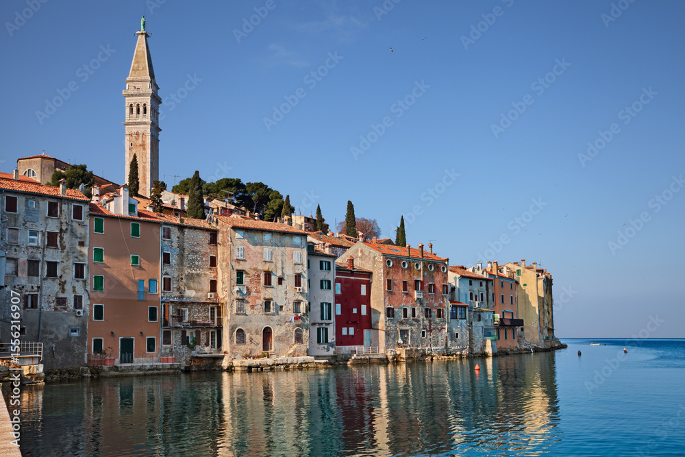 Fototapeta premium Rovinj, Istria, Croatia: a sunrise landscape of the town overlooking the Adriatic Sea, with its old colorful houses and the bell tower of the ancient church