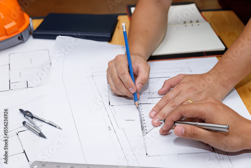 Close-up of architect hands working on a house plan with pencil and ruler on blueprint. Concept of architecture, precision, and technical drawing in a professional workspace.