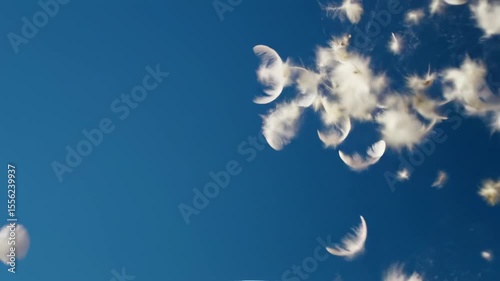 White pillow with falling feathers against a clear blue sky