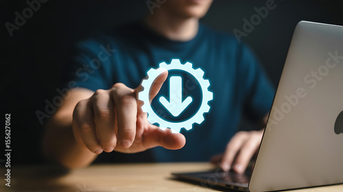 Person s finger touching a glowing blue gear icon with a downward arrow inside symbolizing download or process