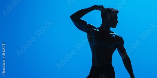 Male model in a dynamic pose against a vibrant blue background with studio lighting highlights his strong, toned muscles.