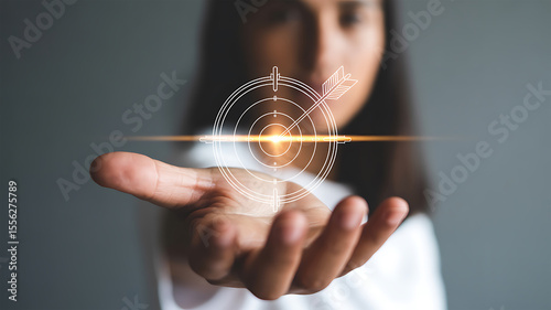 Woman s outstretched hand presents a glowing digital target with an arrow hitting the bullseye