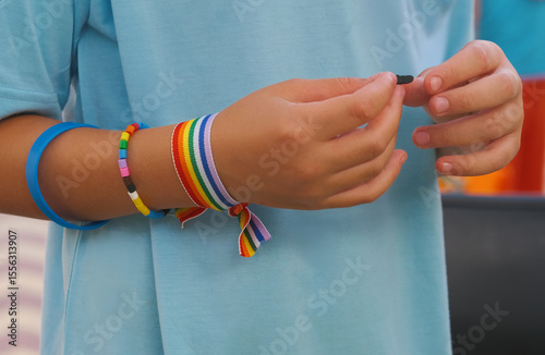Manos de un joven con pulseras de colores del arcoíris apoyo lgtbi