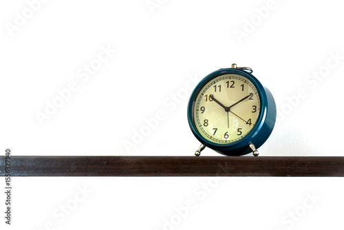 Vintage blue alarm clock displaying time at 10:10 placed on dark wooden shelf with clean white background photo