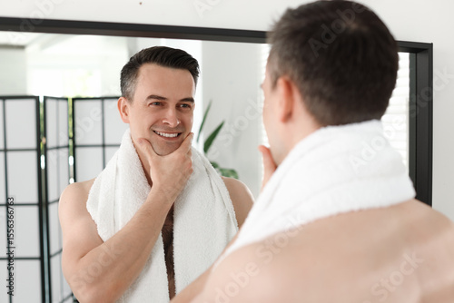 Tableau sur toile Smiling man after shaving looking at mirror in bathroom