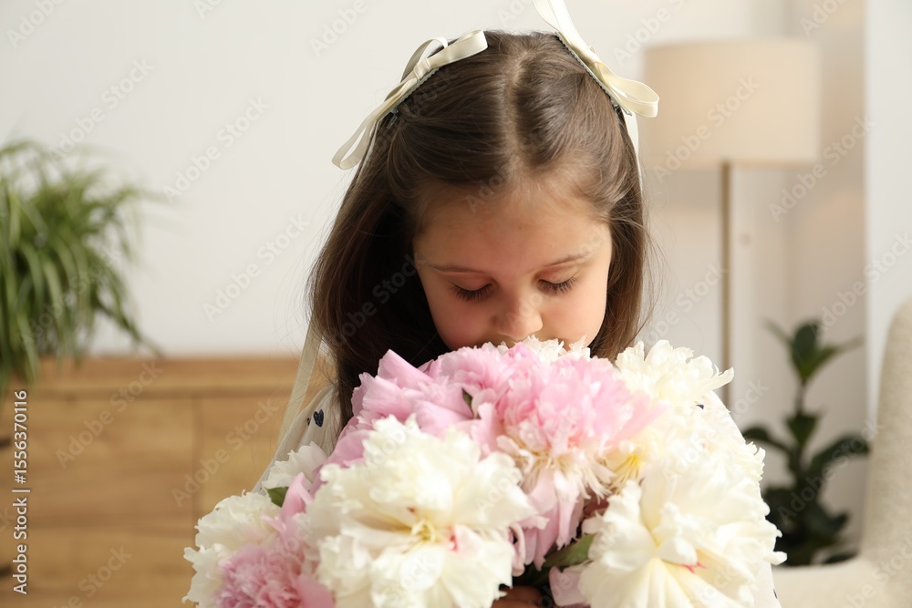 Naklejka premium Cute little girl with bouquet of beautiful peonies at home