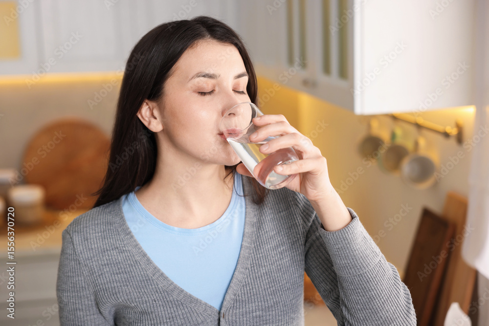 Woman drinking water from glass in kitchen Woman drinking water from glass in kitchen