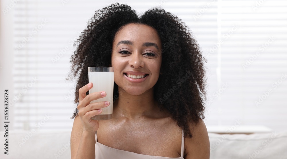 Beautiful Brazilian woman with glass of collagen water indoors Beautiful Brazilian woman with glass of collagen water indoors