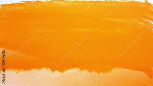Vibrant orange paint flows and spreads across surface creating dynamic abstract patterns with smooth fluid motion and warm color gradients perfect for creative design backgrounds