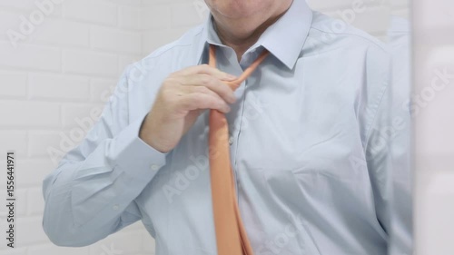 Blurred Shooting with a Borred Businessman in the Mirror Wearing a Blue Shirt and Untying a Tie from His Neck.