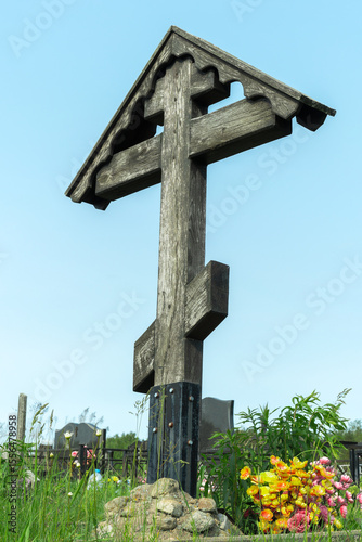Old wooden cross standing tall in a peaceful resting place reflecting the beauty of life and the inevitability of death. Wooden cross in a serene cemetery landscape.