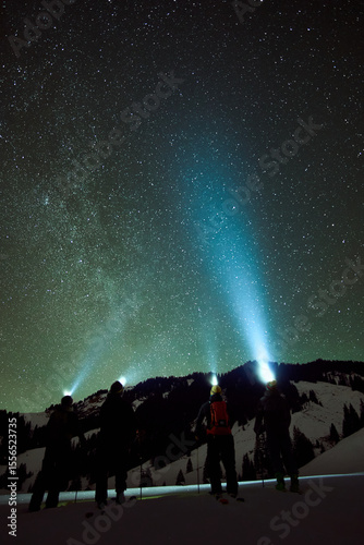 Nighttime mountain adventure in the Alps with starlit sky and headlamps illuminating snowy landscape