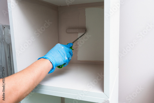 Hand Applying Fresh Paint Inside Cabinet With Roller