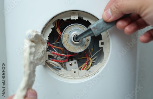 Removing electric heater water heater. Technician removes limescale residue. Problematic calcium deposit on internal element. Maintenance cleaning service. Repairing heating equipment. Corrosion.