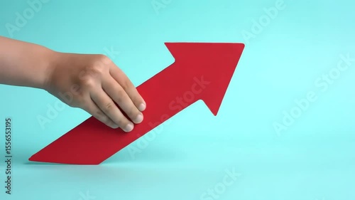 Wallpaper Mural A hand pushes a red arrow upwards on a solid light blue background, indicating growth and forward movement Torontodigital.ca