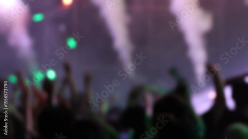 Bokeh view of people dancing on the dance floor during a concert at a festival. Blurred background footage. Concept of crowd enjoying rock and roll, live dj set, hip hop rap party, night club event.