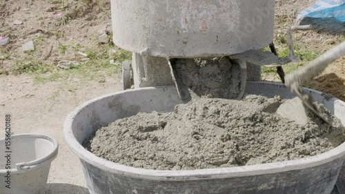 Close-up of a cement mixer blending gray mortar and sand, blades visible as they stir materials for a durable mix.