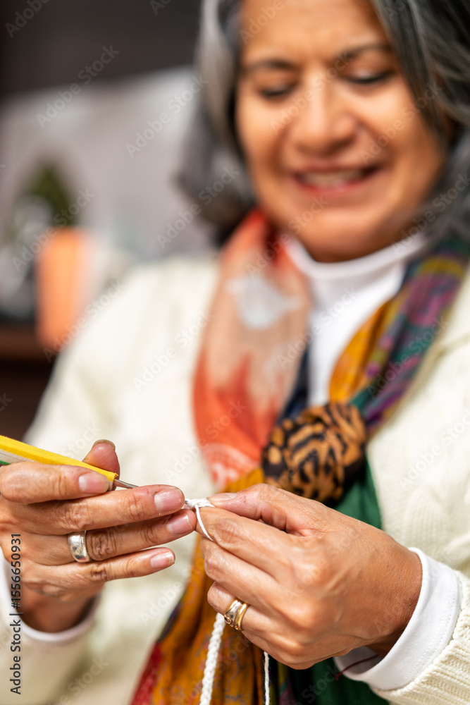 Obraz premium Senior woman knitting with white yarn and yellow needle
