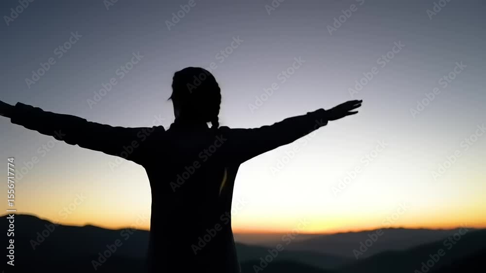 Silhouette of a person with arms outstretched against a vibrant sunset backdrop in nature Silhouette of a person with arms outstretched against a vibrant sunset backdrop in nature