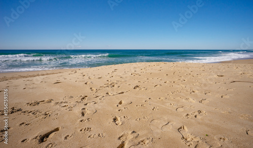A popular tourist beach scene. Lots of footprints in the sand where people and dogs have been. With copy space.