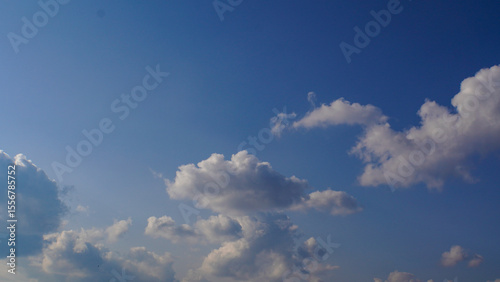 Serene view of a bright blue sky with fluffy white cumulus clouds on a clear sunny day, a natural atmospheric background