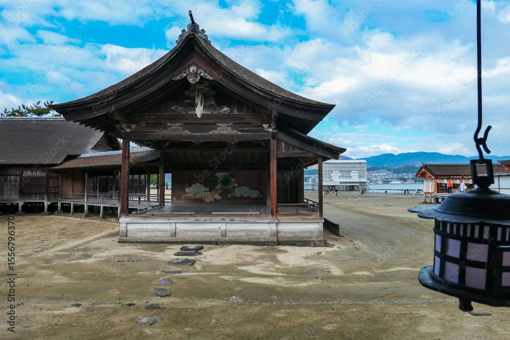 Obraz premium Historic wooden Noh stage at Itsukushima Shrine stands on the tidal flats during low tide. This unique view from Japan's sacred Miyajima island shows the UNESCO World Heritage site's architecture