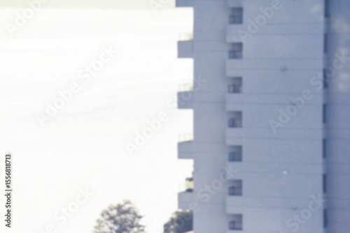 Displaying flat design facade on right with balconies, windows, power lines and treetops under sky
