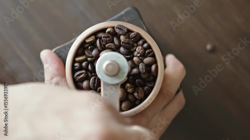 Grinding of aromatic coffee beans with a manual coffee grinder. Smooth rotation of the camera. Top view