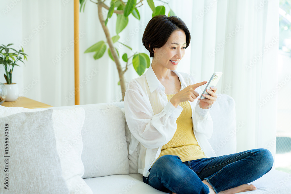 部屋でスマホを使うミドル女性 部屋でスマホを使うミドル女性