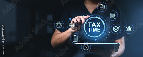 Business person interacting with digital tax time interface using tablet in futuristic office environment with finance and time management icons.