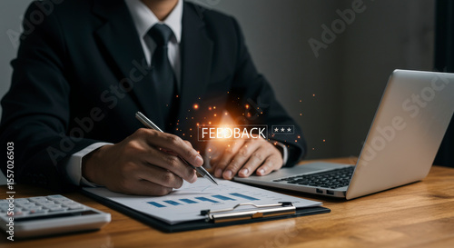 Businessman in Dark Suit Analyzing Graph Report at Wooden Desk with Laptop and Feedback Text Overlay in Brightly Lit Office