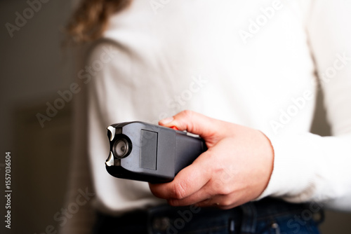 Fotografija Close-up woman's hand holding electric shocker for self defense, Caucasian femal