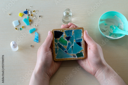 Completed handmade mosaic coaster in mold with dried white gypsum and embedded decorative glass-like fragments viewed from top, step 6