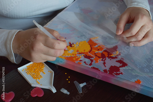 Closeup of hands applying colorful beads to a diamond painting canvas creating a vibrant mosaic perfect for DIY crafting tutorials art workshops and handmade creative projects