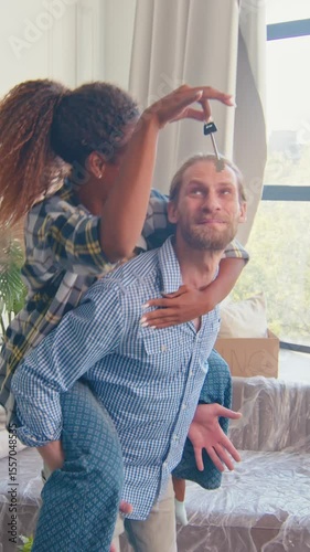 Young diverse couple enjoys the excitement of moving into their new house, sharing moments filled with laughter and connection while unpacking and settling into their new space.