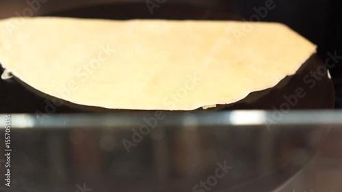 making fresh crepe on hot griddle in street food market close up of thin batter cooking process traditional french pancake preparation golden surface sizzling on hotplate during outdoor food festival