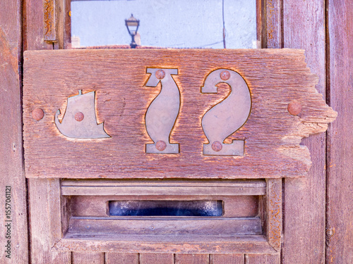 Small metal house number on wooden plate