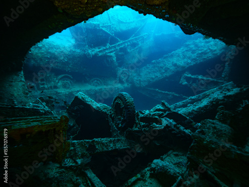 Wrack of the SS Thistlegorm, view from inside a dark cargo bay to the outside, a lonesome wheel standing in the middle