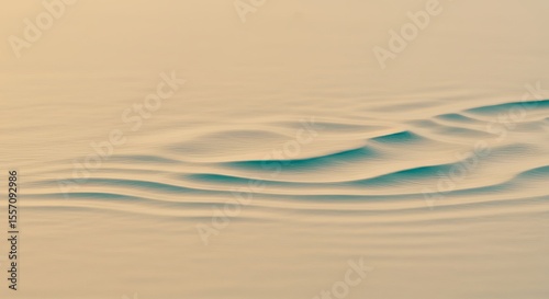 Close-up of small waves on a body of water with a light tan and teal color palette.