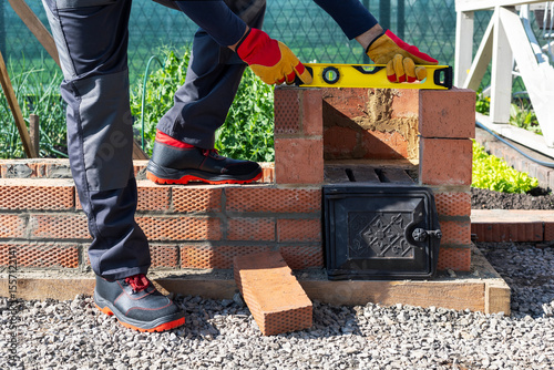  bricklayers hands using spirit level on brick. man builds an oven and checks the wall with a spirit level.