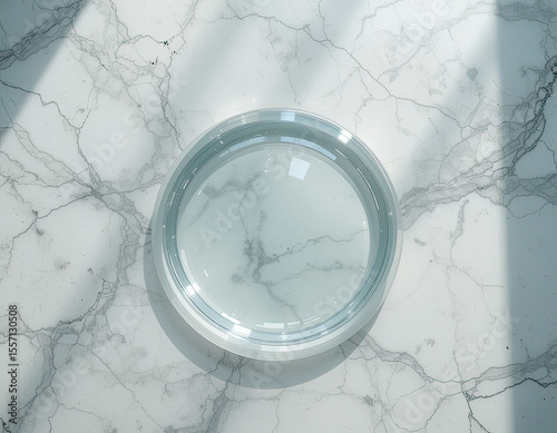 Top view of empty round glass plate on white marble table with soft natural sunlight and shadow, minimal food background for product mockup or design template