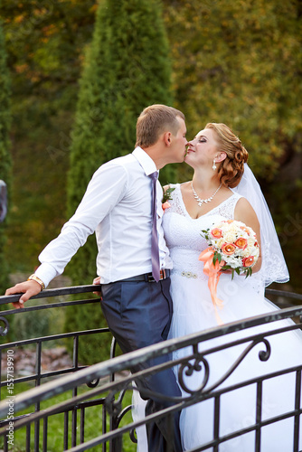 A bride and groom kiss on a bridge