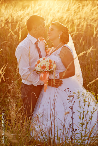 A bride and groom are standing in a field of tall grass