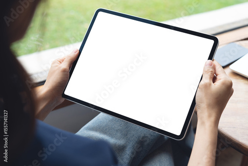 Mockup balnk screen digital tablet. Woman holding digital tablet with blank white screen with laptop computer on table at coffee shop, template for web app design or social media marketing